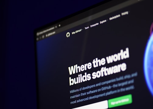 A computer screen displays a website with the text 'Where the world builds software' prominently featured. Below the text, there are fields for users to input their email address, along with additional descriptions about the platform and its capabilities. The website has a dark background with bright text, indicating a professional tech-based service.